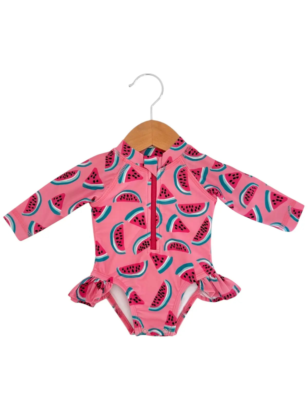 Pink children's swimsuit with watermelon pattern on a hanger against a white background
