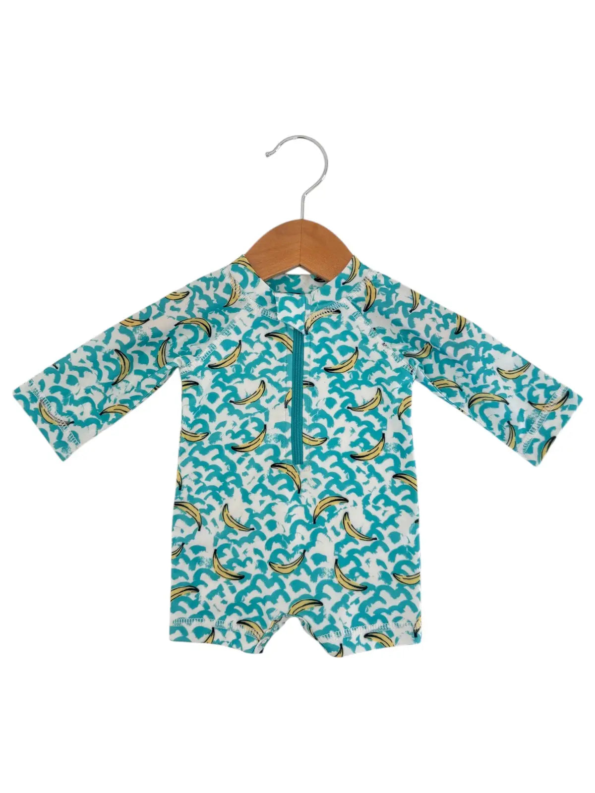 toddler bathing suit with banana pattern on a hanger against a white background