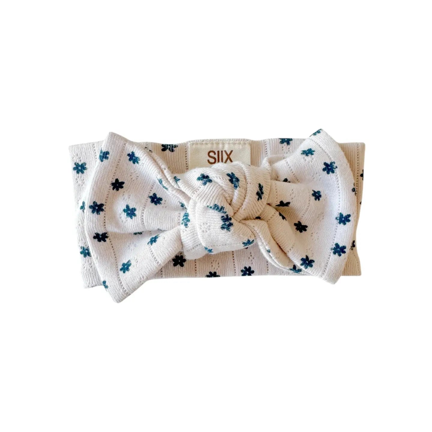 White headband with a bow and blue floral pattern on a white background