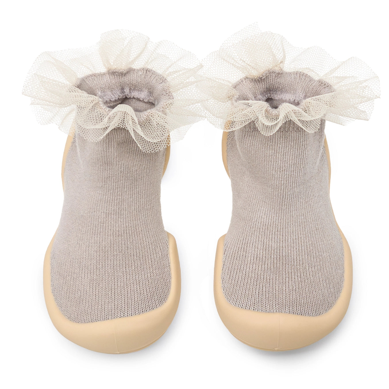 A pair of Komuello toddler shoes with tulle trim on the top, in a beige color, with non-slip soles.