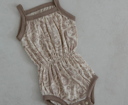 A beige and brown baby cotton bodysuit with a floral pattern, short sleeves, and a round neckline.