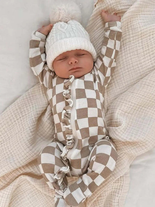 A baby footie with a checkerboard pattern and frill along the zipper.