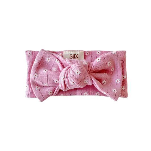 Pink headband with a bow and floral details on a white background