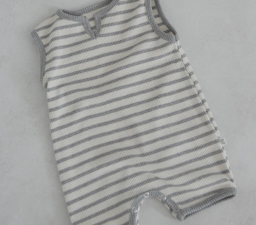 A striped baby romper overall made of organic cotton, predominantly white with gray stripes, showing the romper's button and a small amount of spandex fabric.