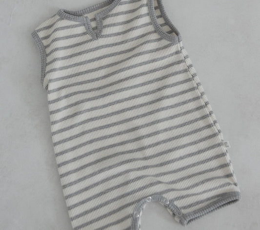 A striped baby romper overall made of organic cotton, predominantly white with gray stripes, showing the romper's button and a small amount of spandex fabric.